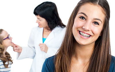 Young girl with braces and dentist in background