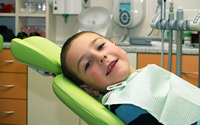 A young boy smiling in a dental chair