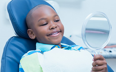 Child holding mirror in dental chair