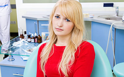 Woman in dental office looking unhappy