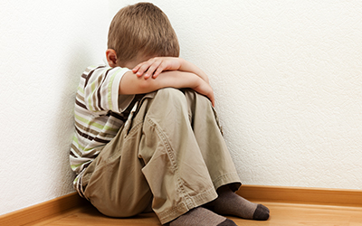 A young boy in a corner with his head down