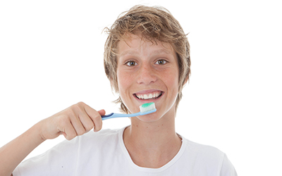 A teen boy brushing his teeth