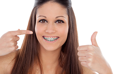 Young girl with orthodontic braces with thumbs up