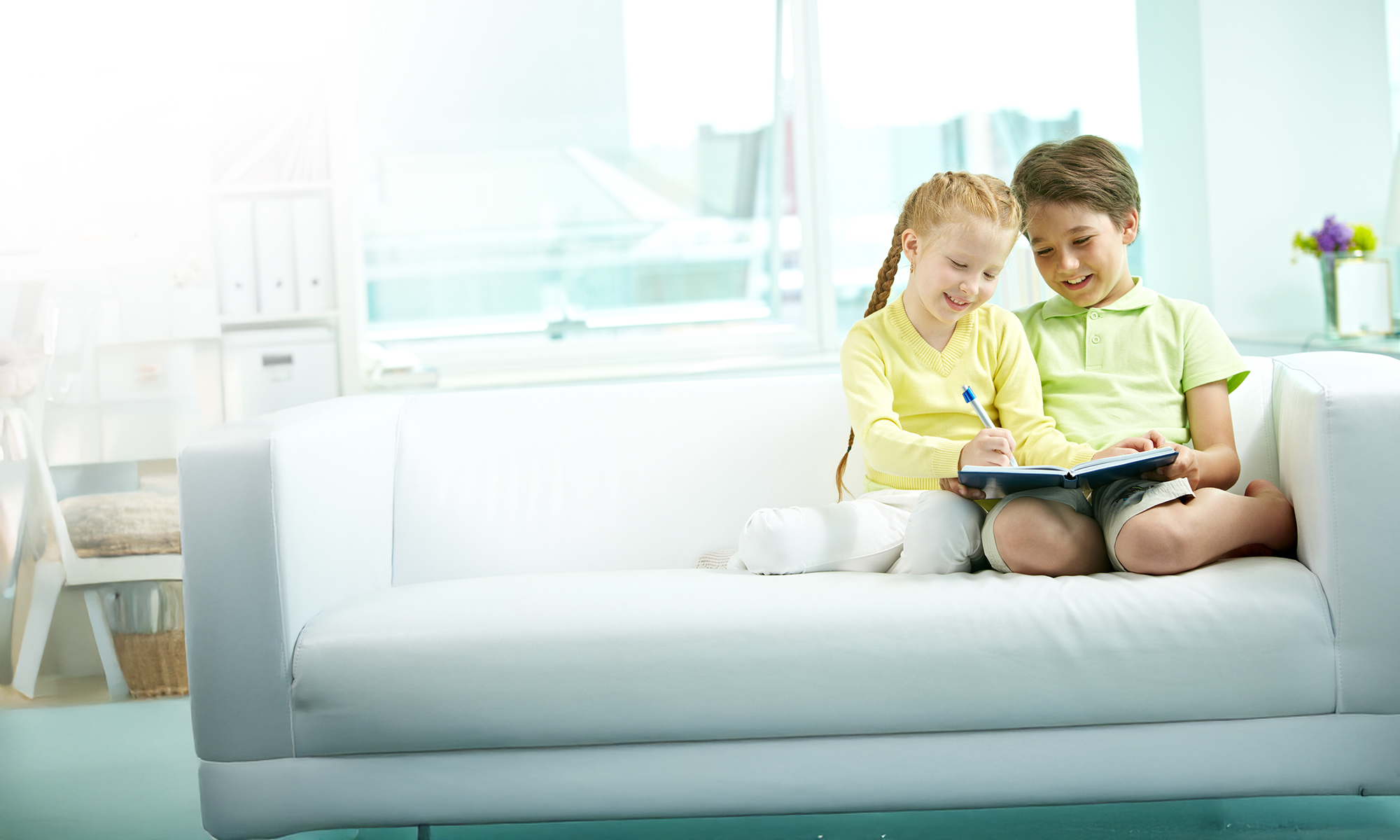 Two kids on a couch looking at a mobile device