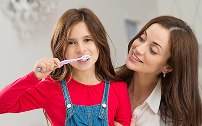 Child brushing with her mom